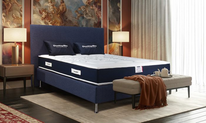 Un matelas avec mousse à mémoire de forme visco aérial avec un sommier et tête de lit en bleu foncé.